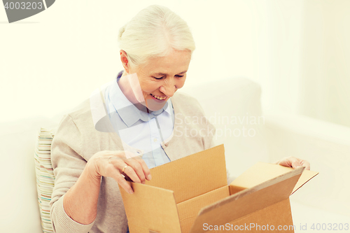 Image of happy senior woman with parcel box at home