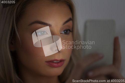 Image of young woman with smartphone at night