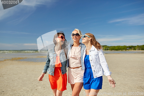 Image of group of smiling women in sunglasses on beach