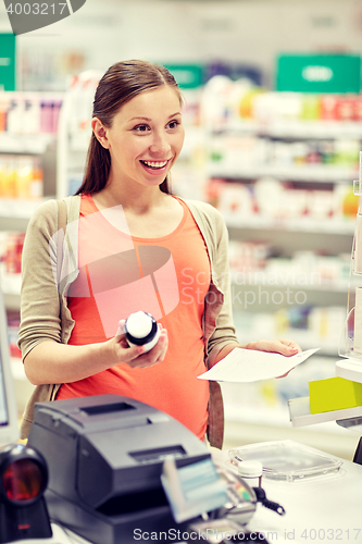 Image of happy pregnant woman with medication at pharmacy