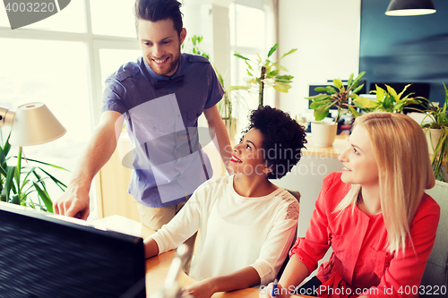 Image of happy creative team with computer in office