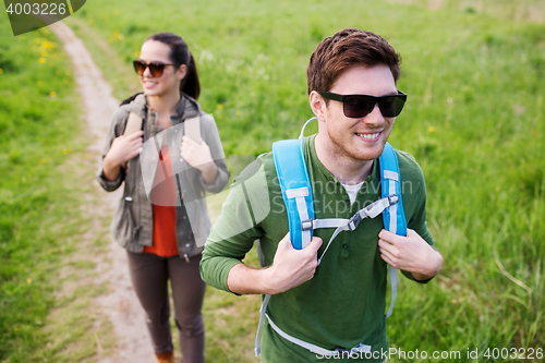 Image of happy couple with backpacks hiking outdoors