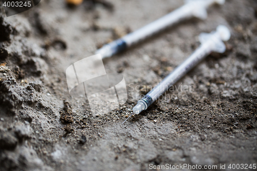 Image of close up of used drug syringes on ground