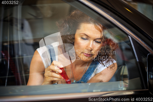 Image of emale mechanic repairing a car door with a screwdriver