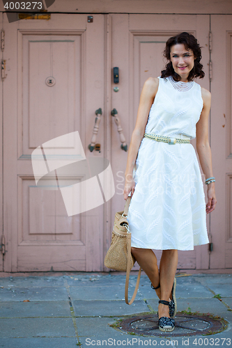 Image of smiling dark-haired middle-aged woman dressed in a light summer 