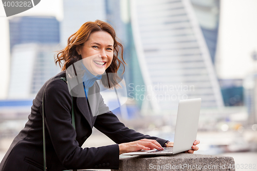 Image of portrait of a beautiful laughing woman with a laptop