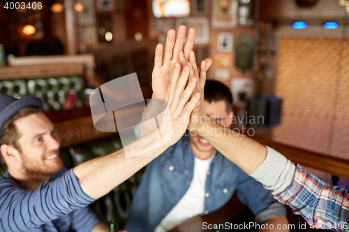 Image of close up of friends making high five at bar or pub