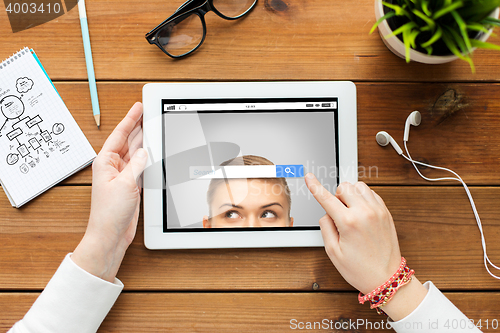 Image of close up of woman with tablet pc on wooden table