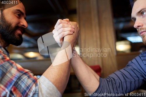 Image of close up of men arm wrestling at bar or pub