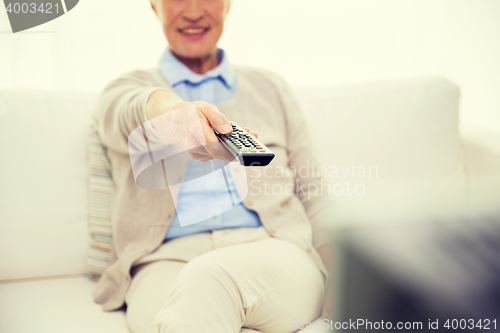 Image of close up of happy senior woman watching tv at home
