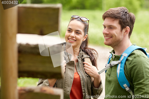 Image of smiling couple at signpost with backpacks hiking