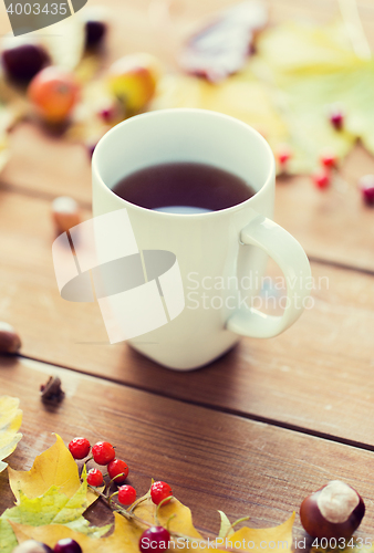 Image of close up of tea cup on table with autumn leaves
