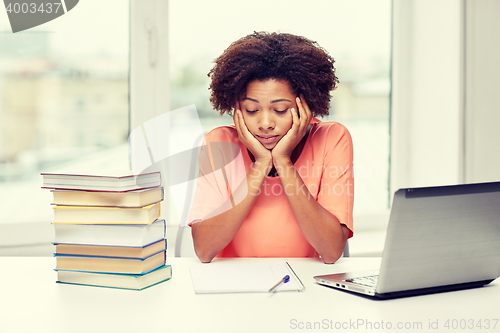 Image of bored african american woman doing homework home