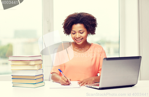 Image of happy african american woman with laptop at home