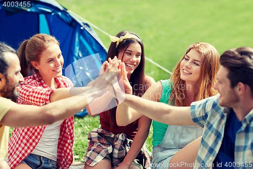 Image of happy friends making high five at camping