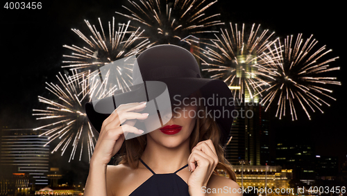 Image of beautiful woman in black hat over night firework