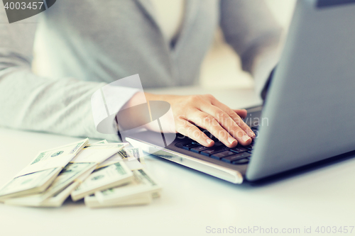 Image of close up of woman hands with laptop and money
