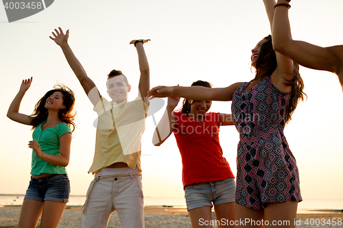 Image of smiling friends dancing on summer beach