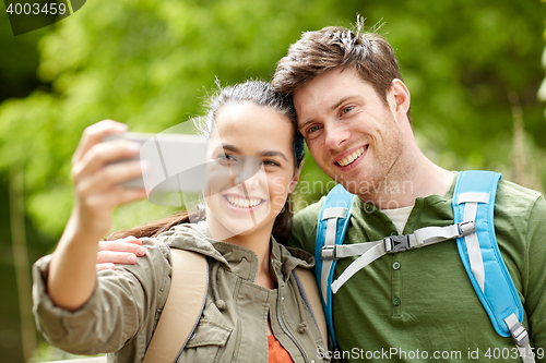 Image of couple with backpacks taking selfie by smartphone