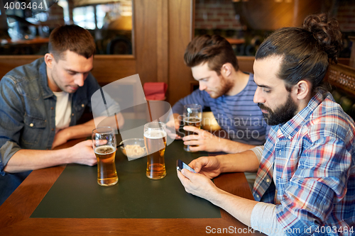 Image of men with smartphones drinking beer at bar or pub