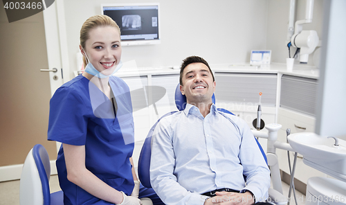 Image of happy female dentist with man patient at clinic