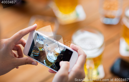Image of close up of hands with smartphone picturing beer