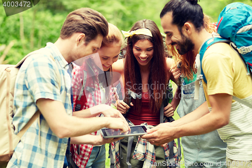 Image of happy friends with backpacks and tablet pc hiking