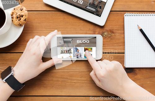 Image of close up of woman with smartphone on wooden table