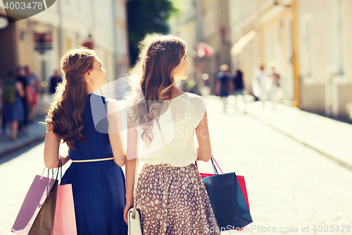 Image of happy women with shopping bags walking in city 