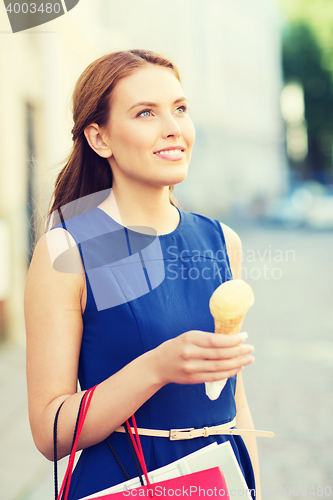 Image of woman with shopping bags and ice cream in city