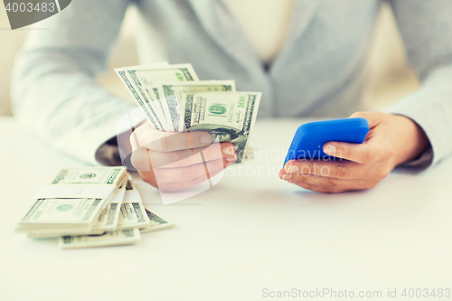 Image of close up of woman hands with smartphone and money