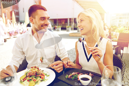 Image of happy couple eating dinner at restaurant terrace
