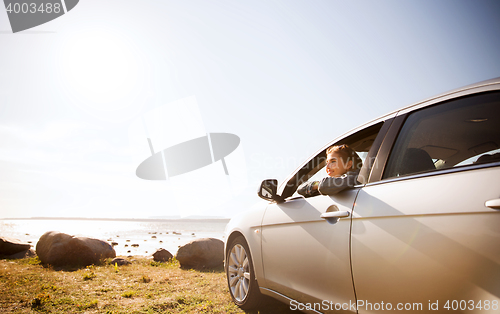 Image of happy teenage girl or young woman in car