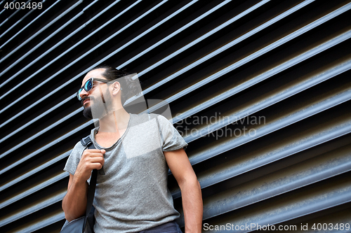 Image of man with backpack standing at city street wall