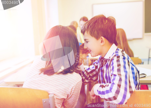 Image of smiling schoolgirl whispering to classmate ear