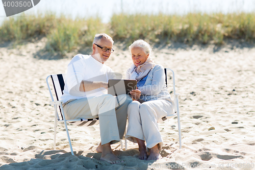 Image of happy senior couple with tablet pc on summer beach