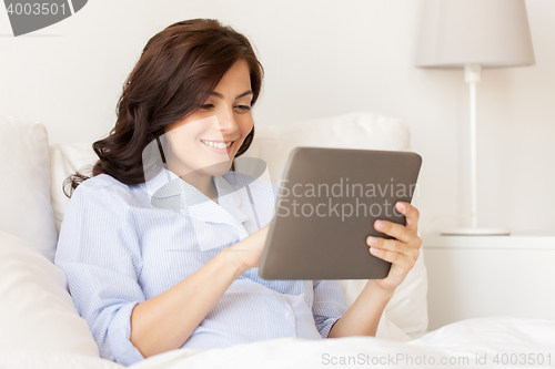 Image of happy pregnant woman with tablet pc at home
