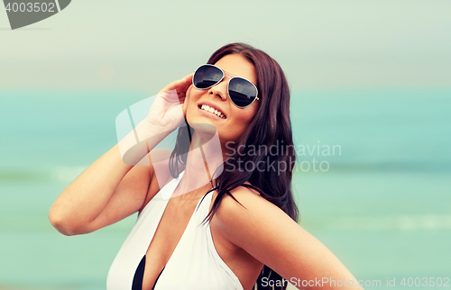 Image of smiling young woman with sunglasses on beach