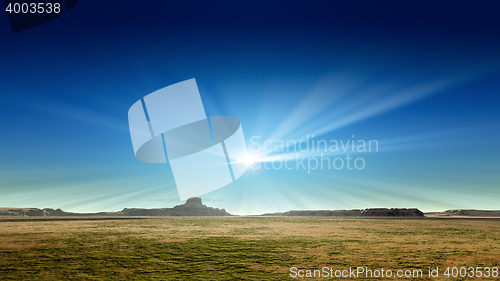 Image of a desert scenery with sun rays in the blue sky