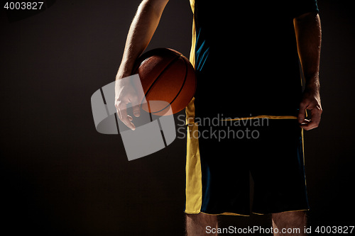 Image of Silhouette view of a basketball player holding basket ball on black background