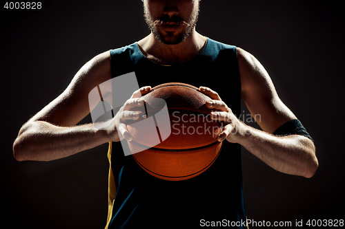 Image of Silhouette view of a basketball player holding basket ball on black background