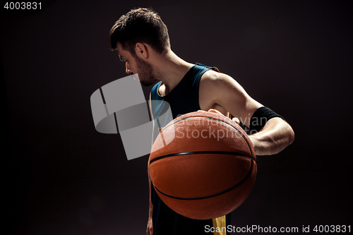 Image of Silhouette view of a basketball player holding basket ball on black background