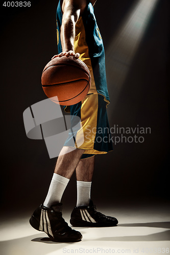 Image of Silhouette view of a basketball player holding basket ball on black background