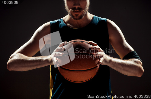 Image of Silhouette view of a basketball player holding basket ball on black background