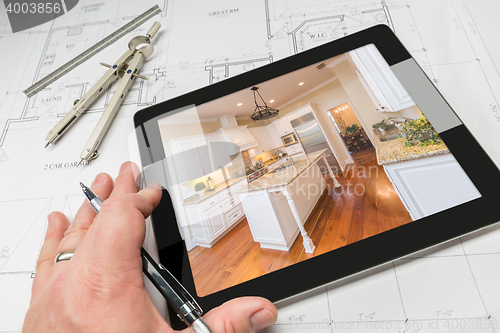 Image of Hand of Architect on Computer Tablet Showing Kitchen Photo Over 