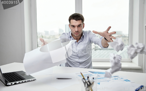 Image of angry businessman throwing papers in office