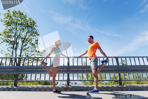 Image of smiling couple stretching outdoors