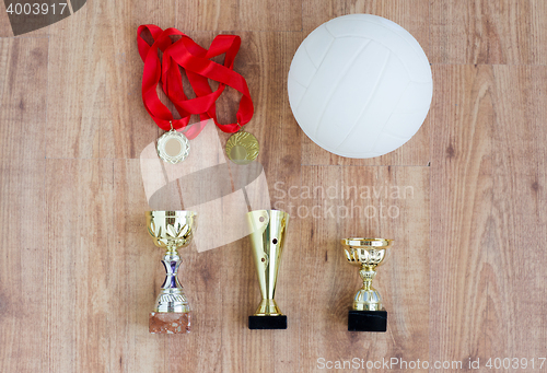 Image of close up of volleyball ball, cups and medals