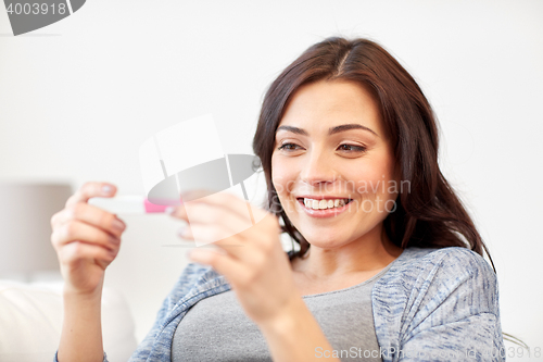 Image of happy woman looking at home pregnancy test