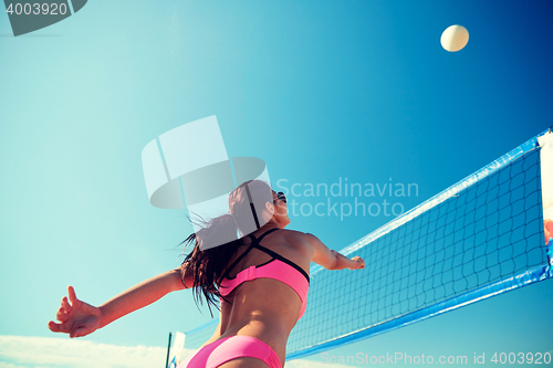 Image of young woman with ball playing volleyball on beach